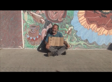 Beggar against a wall with painted mural