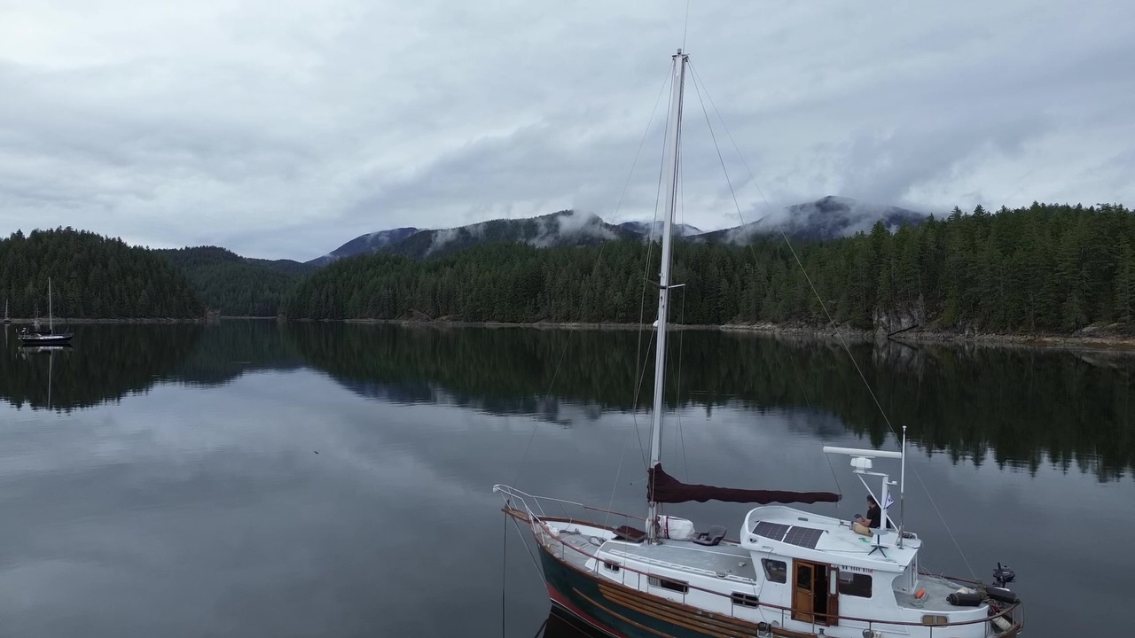 Sailboat anchored in calm bay with mountains